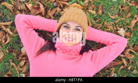 Donna sdraiata su foglie di autunno, ritratto all'aperto Foto Stock