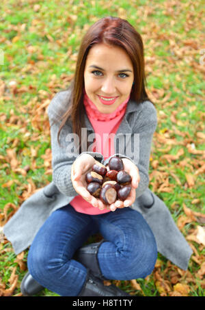 Ragazza con molti castagne nelle sue mani Foto Stock