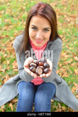 Ragazza con molti castagne nelle sue mani Foto Stock