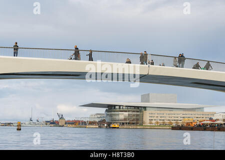 Persone sul ponte pedonale e ciclista di Inderhavnsbroen con l'Opera House Operaen di Copenaghen sullo sfondo, Copenhagen, Danimarca Foto Stock