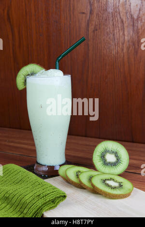 Un sano frullato verde realizzato da kiwi verde con cannucce su un tavolo di legno. Foto Stock