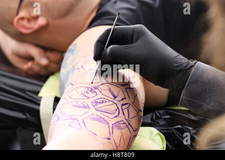 Disegno Tatoo sulla sua spalla. Tatuaggio, tattoo artist fa il tatuaggio su la mano dell'uomo. Foto Stock