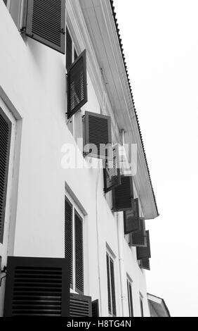 Fila di finestre al piano superiore dell'edificio vista dall'esterno al piano terra. La fotografia in bianco e nero. Foto Stock