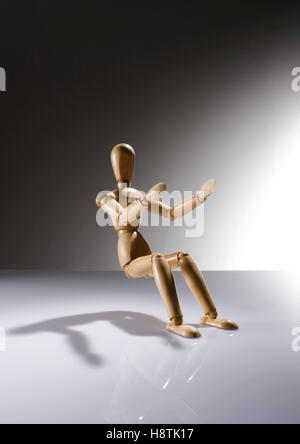 Manichino di legno bambola seduta senza una sedia sul gradiente dello sfondo Foto Stock