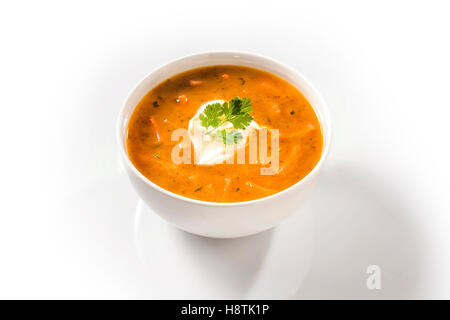 Crema di zuppa di carota in una tazza bianca guarnita con panna acida Foto Stock