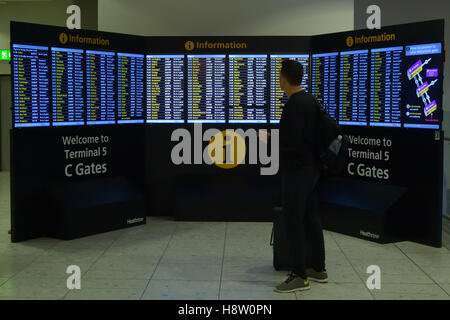 Il passeggero che cercano i dettagli del volo all'aeroporto di Londra Heathrow Terminal 5, UK (LHR / EGLL) Foto Stock