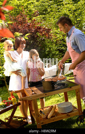 Famiglia avente un barbecue nel giardino Foto Stock