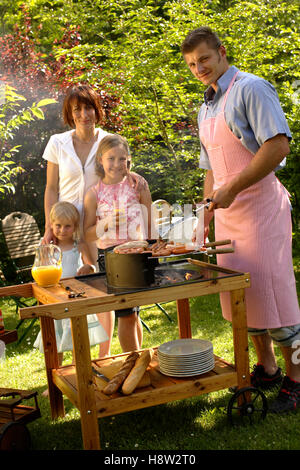 Famiglia avente un barbecue nel giardino Foto Stock