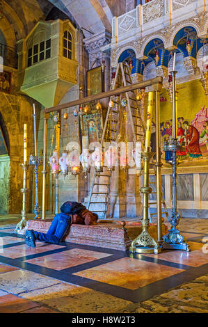 L adoratore uomo sulle ginocchia bacia la pietra della unzione nella chiesa del Santo Sepolcro Foto Stock