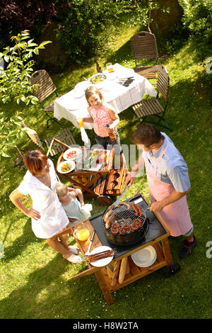 Famiglia avente un barbecue nel giardino Foto Stock