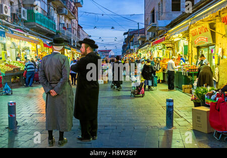 Due amici-hasids, vestito in un tradizionale ed elegante abiti, parlando all'entrata di Mahane Yehuda Market Foto Stock