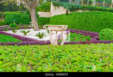 Il bianco fontana in pietra, decorata con sculture complesse tra il verde del giardino Bahai, Haifa, Israele. Foto Stock