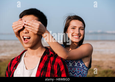 Felice carino giovane donna gli occhi coperti da mani al suo fidanzato all'aperto Foto Stock