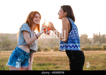 Due allegro carino giovani donne a bere la soda e divertimento all'aperto Foto Stock