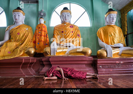 Monaco birmano dormire nella parte anteriore delle statue di Buddha Foto Stock