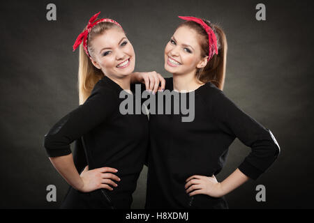 Amore e Affetto in famiglia. Splendida bionda sorelle stilizzata sul retro pin up in stile vintage. Due ragazze nel fazzoletto rosso sorridente piacevole sentire hap Foto Stock