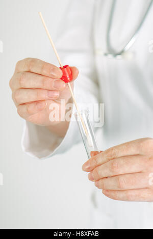 Femmina specialista medico tenendo buccale un batuffolo di cotone e il tubo di prova, pronto a raccogliere il DNA da cellule all'interno di una persona della guancia Foto Stock