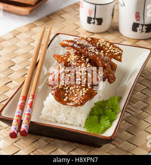 Pollo Teriyaki servito con riso su una piastra rettangolare. Foto Stock