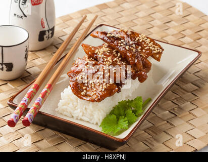 Pollo Teriyaki servito con riso su una piastra rettangolare. Foto Stock