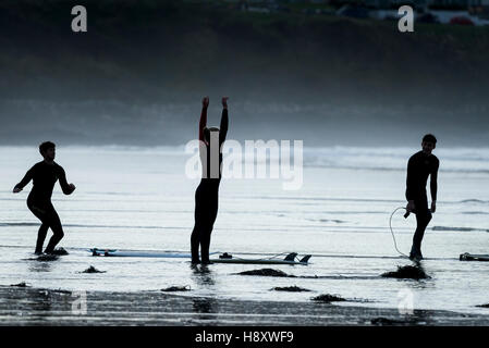 Tre i surfisti si prepara a navigare a Fistral in Newquay, Cornwall. Foto Stock