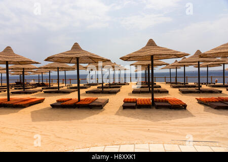 Lo splendido paesaggio di spiaggia con lettini in legno, ombrelloni di paglia e il mare Foto Stock