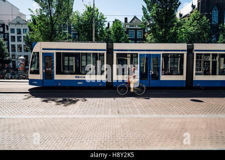 Amsterdam, Paesi Bassi - 1 agosto 2016: l'uomo in sella ad una bicicletta e tram in strada a Amsterdam. Foto Stock