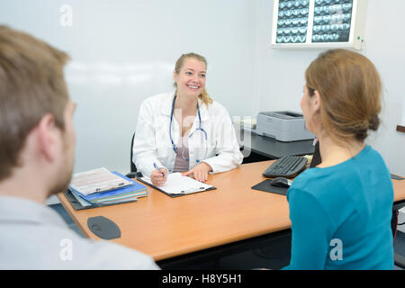 Felice medico dando una buona nuova per una giovane coppia Foto Stock