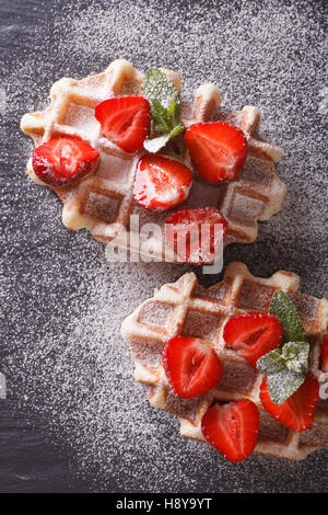 Cialde di Liegi con fragole fresche, lo zucchero in polvere di close-up in ardesia. vista verticale da sopra Foto Stock