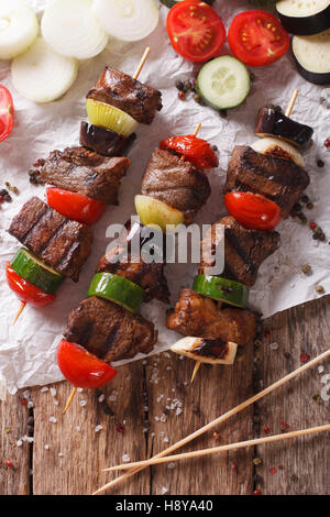 Shish kebab su spiedini con verdure vicino sul tavolo. vista verticale da sopra Foto Stock