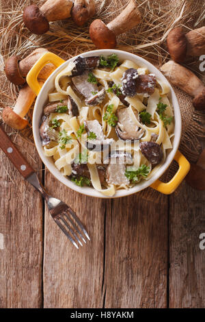 La pasta italiana Le Fettuccine con funghi selvatici in salsa alla panna close-up in una pentola di giallo. Vista verticale da sopra Foto Stock