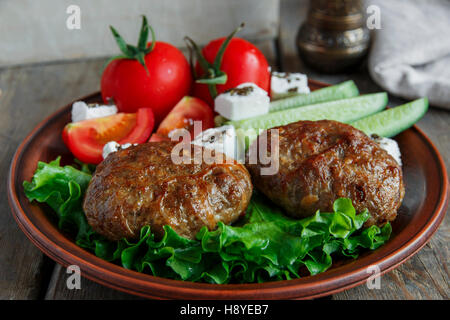 Costolette fritte nella piastra con le verdure sul tavolo di legno messo su una piastra Foto Stock