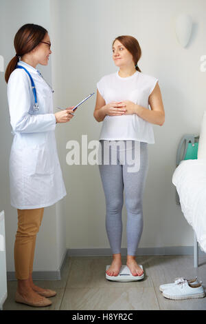 Pazienti in stato di gravidanza in piedi su scale durante la consultazione con il medico Foto Stock