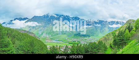 La vista sul resort Stepantsminda nella valle di montagna sopra il bosco di abeti di Kazbegi National Park, Georgia. Foto Stock