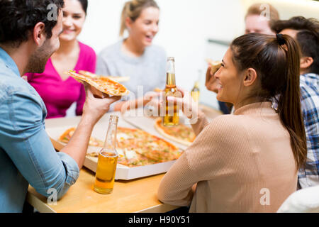 Un gruppo di giovani felici hanno di mangiare pizza e bere il sidro di mele nel moderno arredamento Foto Stock