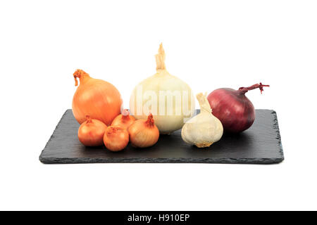 Cipolle, marrone, bianco e viola con gli scalogni e l'aglio sul nero ardesia bordo isolati su sfondo bianco Foto Stock