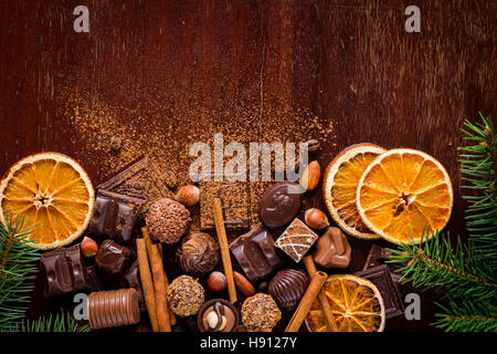 I dolci di natale, cioccolatini, spezie, tartufi di cioccolato e arance essiccate su sfondo di legno con copia spazio orizzontale. Foto Stock