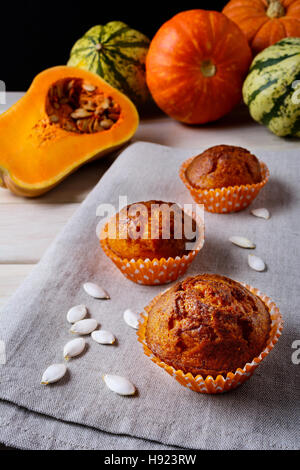 Muffin di zucca in involucri di colore arancione con i semi di zucca. Caduta in casa stagionale cibo vegetale. Sana pasticceria vegetariana. Foto Stock