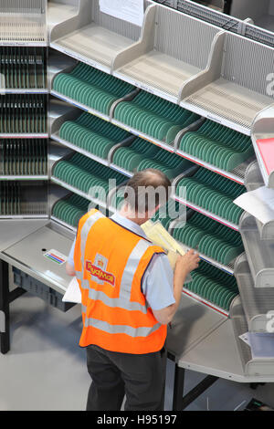 Un singolo postino lavora ad un vuoto di ordinamento scrivania in un nuovo ufficio postale ufficio di smistamento nel sud dell'Inghilterra, Regno Unito Foto Stock