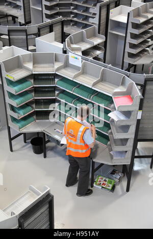 Un singolo postino lavora ad una scrivania di ordinamento in un nuovo ufficio postale ufficio di smistamento nel sud dell'Inghilterra, Regno Unito Foto Stock