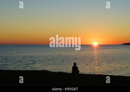 Persona con la visualizzazione di un tramonto sull'oceano. Foto Stock