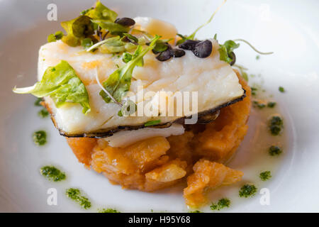 Merluzzo cotto piatto su un letto di patate ed insalata Foto Stock
