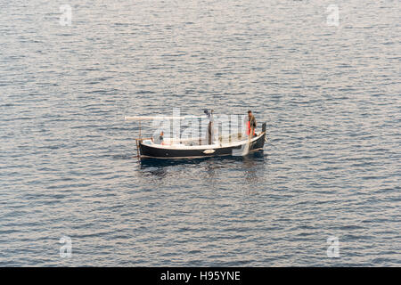 I pescatori in una piccola barca da pesca haul nelle loro reti e catture in Trpanj Croazia sul Mare Adriatico Foto Stock