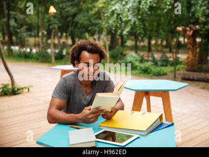 Gravi giovani africani uomo seduto e studiare nel parco Foto Stock