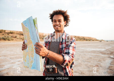 Felice africana uomo giovani turisti con zaino e permanente tenendo mappa all'aperto Foto Stock