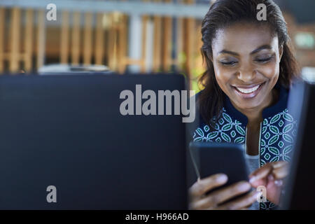 Sorridente imprenditrice texting con un telefono cellulare Foto Stock