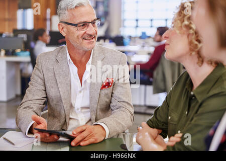 La gente di affari con tavoletta digitale parlando in riunione Foto Stock