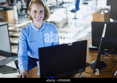 Ritratto sorridente imprenditrice lavora al computer portatile in ufficio Foto Stock