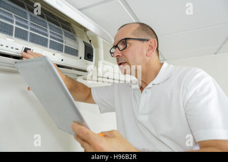 L'uomo controllo aria condizionata manuale mentre l'usando Foto Stock