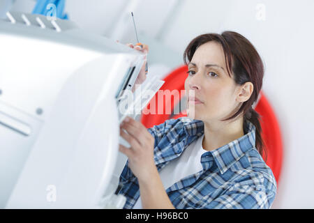 Una donna che fissa una stampante in ufficio Foto Stock