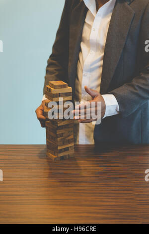 La pianificazione del rischio e della strategia nel business, imprenditore il gioco d'azzardo posizionando il blocco di legno su una torre Foto Stock